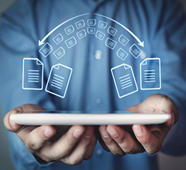 Ręce trzymające tablet nad którym są ikony dokumentów